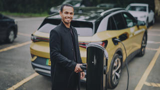 A man charging his electic vehicle at a charge station