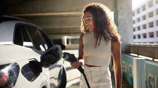 woman at a charge station charging her electric vehicle