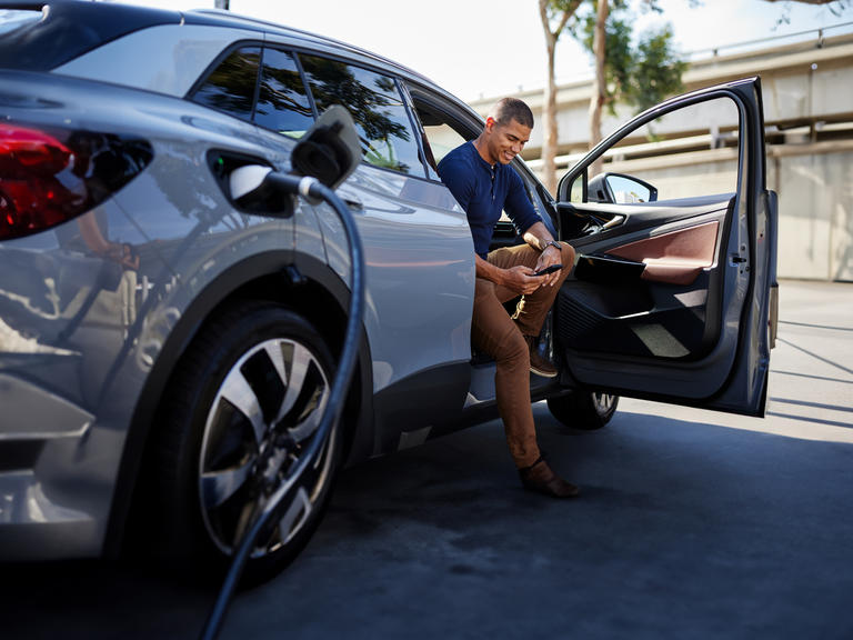 A man plugs in his electric car at an EV charge point