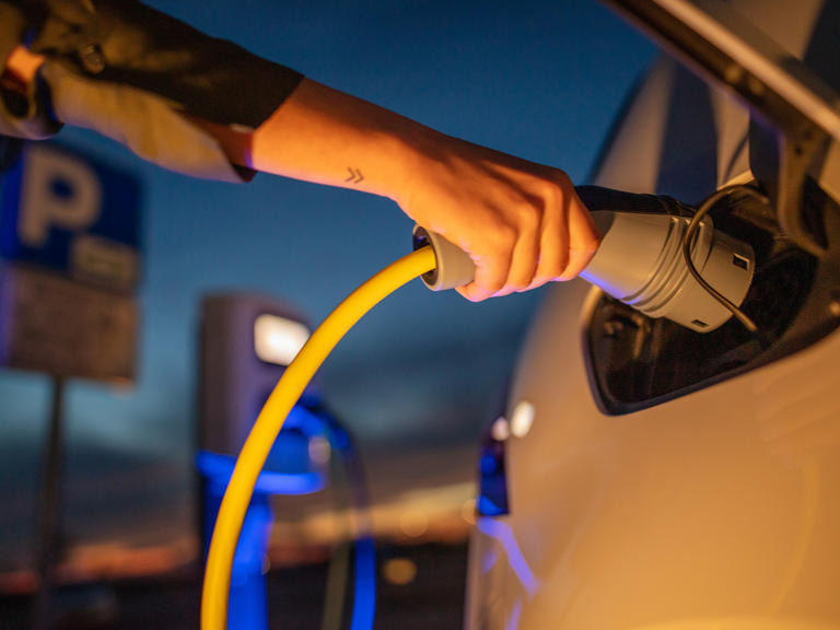A person plugs in their EV into a chargepoint at night.