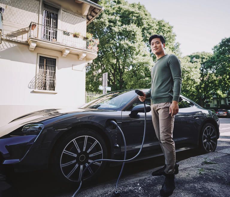 A man holding a charge nozzle to charge his electric vehicle
