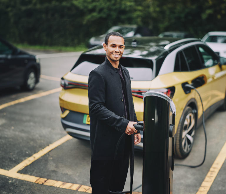 A man charges his electric vehicle at an EV chargepoint.