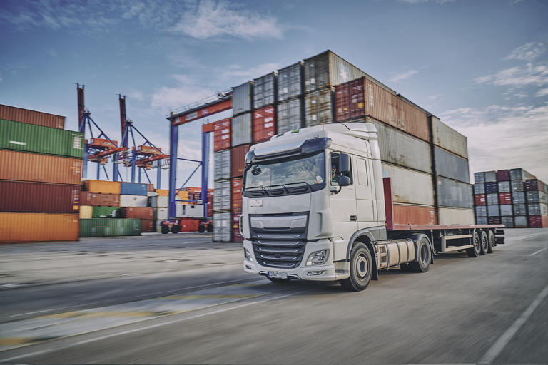 A semi truck driving through a busy port area.