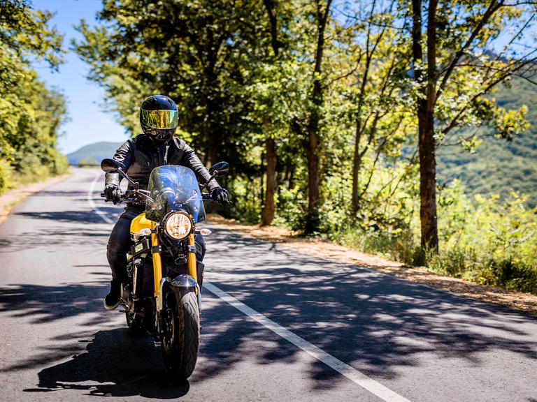 A motorcycle drives on a country highway.