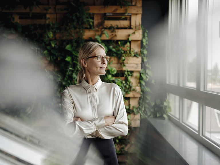 A businesswoman looks confidently out her office window.