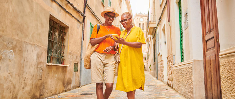 Two women on vacation using their cell phone to navigate through the city.